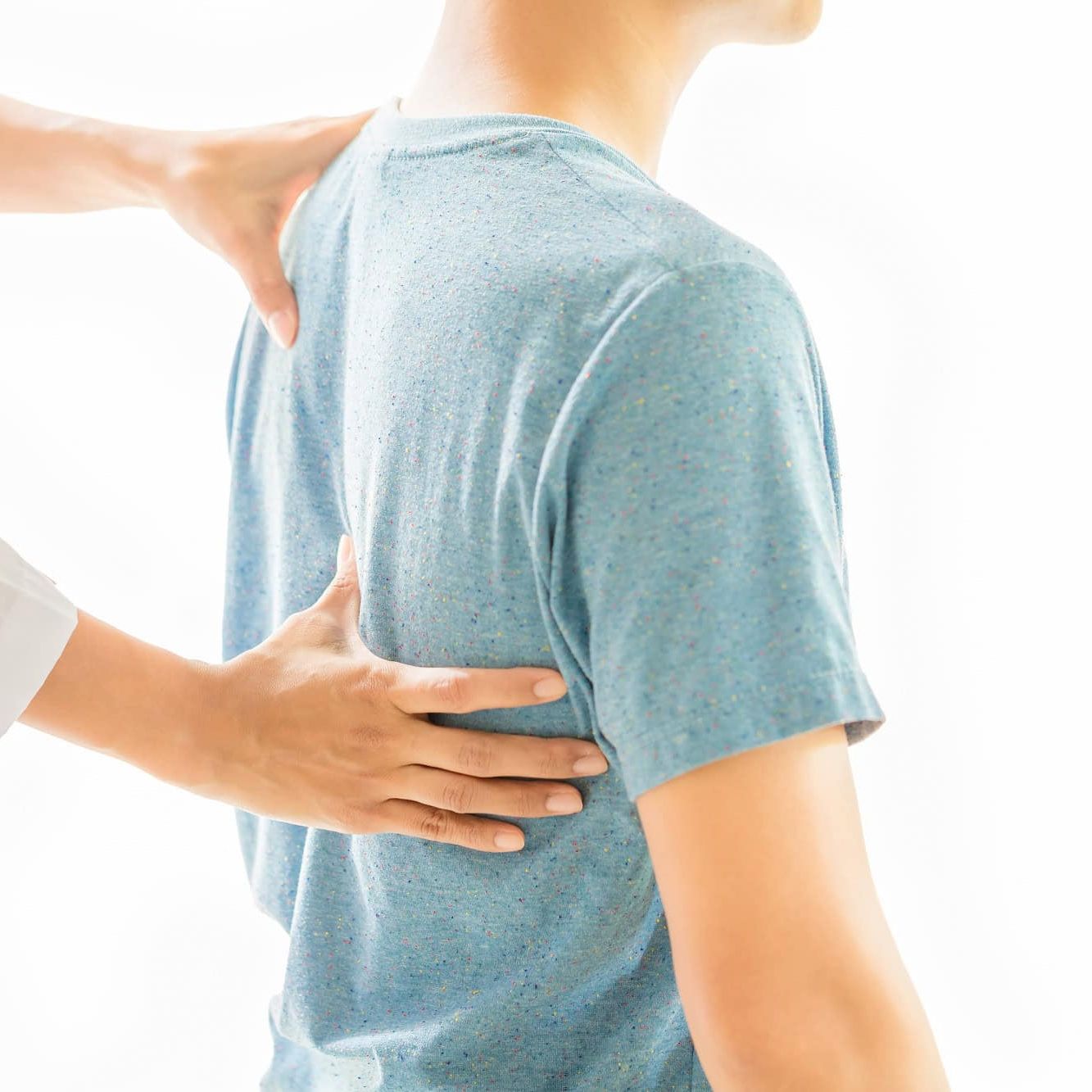 Fysioterapeut kjenner på pasientens øvre rygg og skulder.